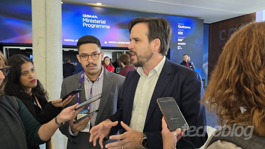 Homem concede entrevista enquanto repórteres gravam com celulares
